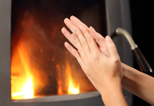 Handing warming in front of Dorako Eco Max 7 3F wood stove on a white background with 691 mm Width in size, 50cm trunk length and transparent glass