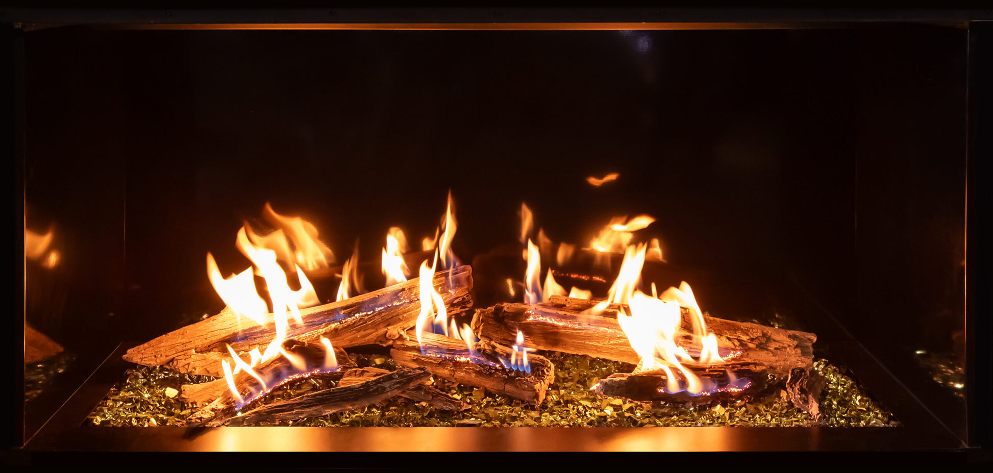 Up close view of Traditional log Gas Glass Fireplace with flames burning in a dark setting