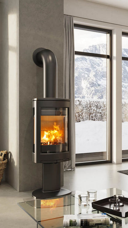 Matte Black Freestanding jotul GF 370 DV IPI Gas stove in a room with large windows showing a snowy landscape.