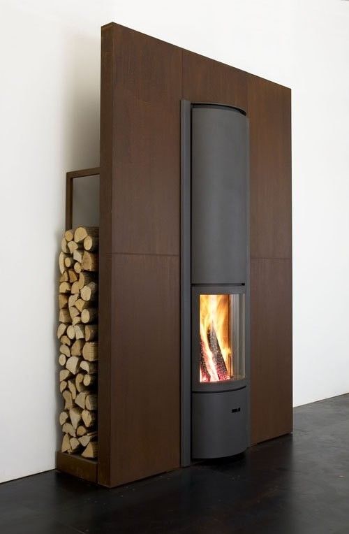 Modern fireplace with a basket of wood on a red and gray wall STUV Modern MCM Fireplace Cylinder fireplace Modern floating fireplace with steel plate for low clearance zero clearance fireplace background Modern wood-burning stove with firewood storage on a white background