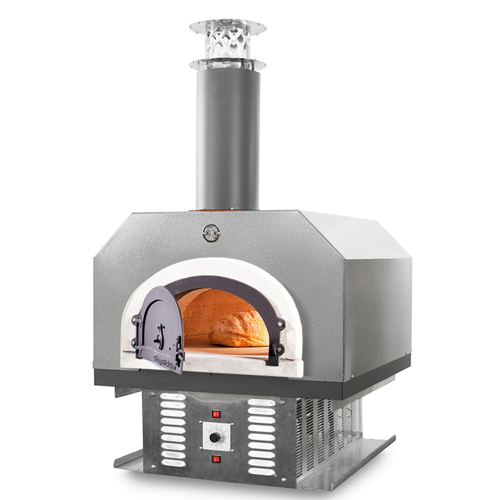 A countertop Chicago Brick Oven 750 Hybrid pizza oven with a visible bread being cooked inside, featuring a silver vein metal exterior and a dark chimney.