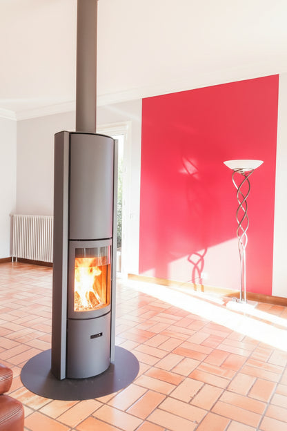 Modern fireplace with a basket of wood on a red and gray wall STUV Modern MCM Fireplace Cylinder fireplace Modern floating fireplace with steel plate for low clearance zero clearance fireplace background Stûv 30 slow-burn wood stove with 360° rotation and up to three operating modes. EPA certified