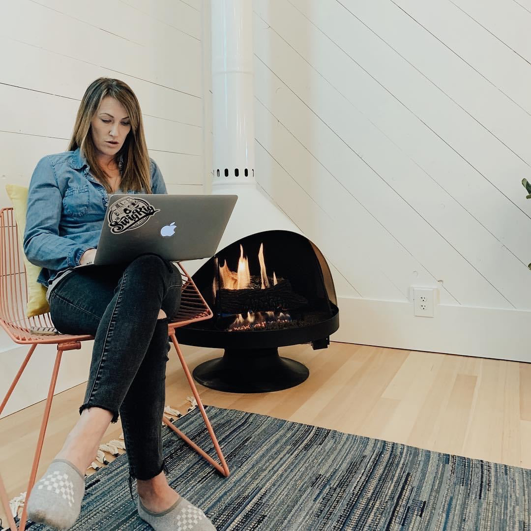 Woman Pressing laptop sitting beside white Malm zircon 34"Electric fireplace with Matte black base