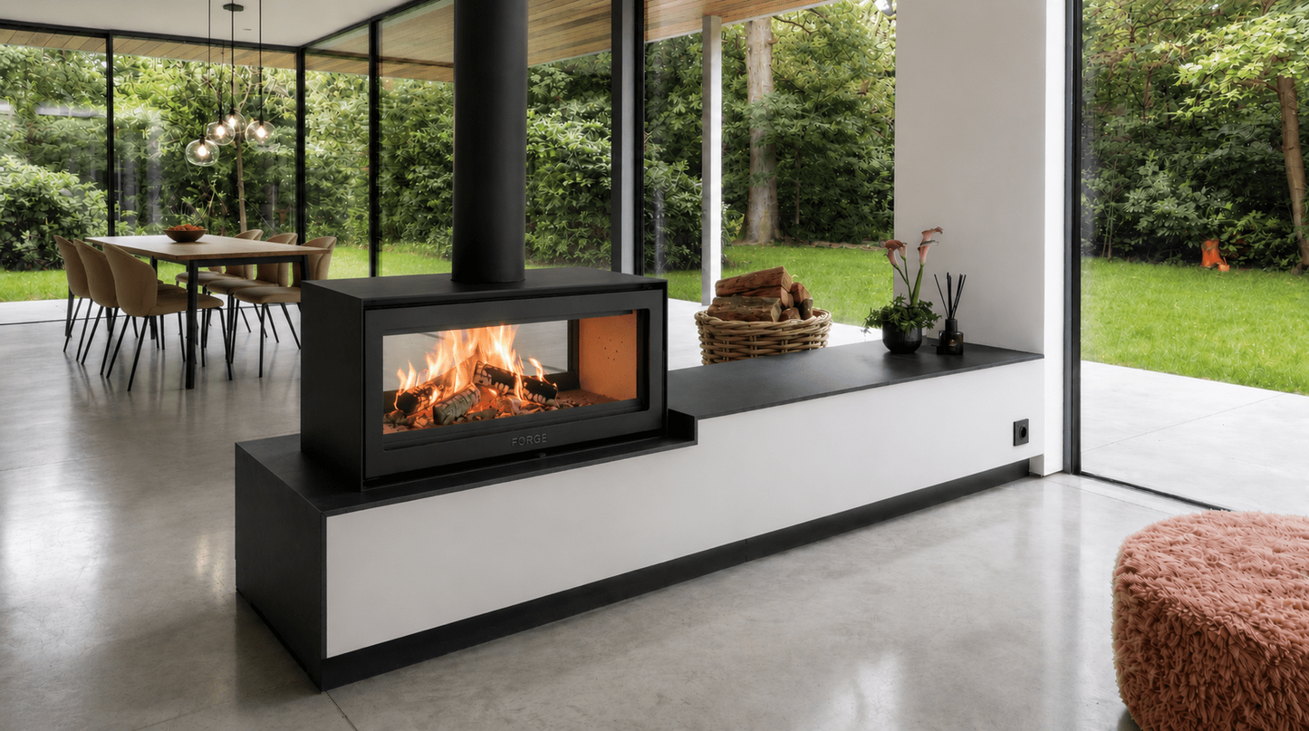 Forge D120 Freestanding double sided wood burning modern indoor fireplace with a visible wood burning flame in a modern living room. MCM fireplace, double door fireplace, See through Fireplace, Eco-friendly fireplace with chimney system. This product is similar to Stuv 21 - 85DF Double Sided Built-In Wood Burning Fireplace with Glass Door, Steel Frame, Stuv 21-95 Double sided Wood Stove with Retractable Glass Door, 48″ Artisan Double-Sided Vent Free Linear Fireplace, IFT 2.0.