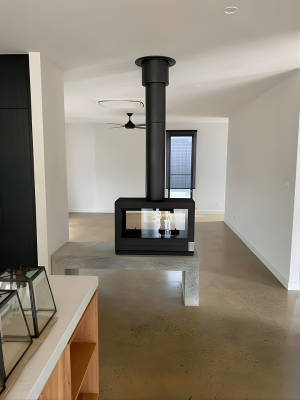 Invicta Aaron Double sided Glass 36" Cast Iron wood burning stove in a middle of a living room.