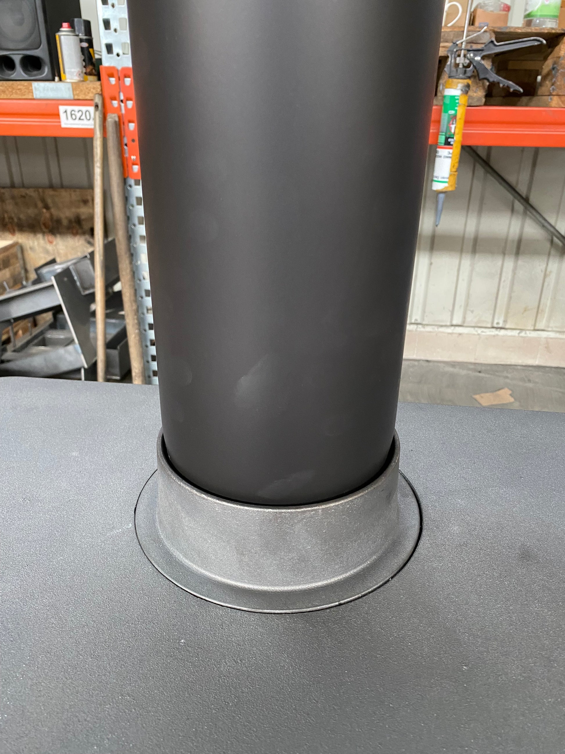 Scandinavian Style Black Dorako STO M14 Wood-burning stove with a chimney in a workshop. 