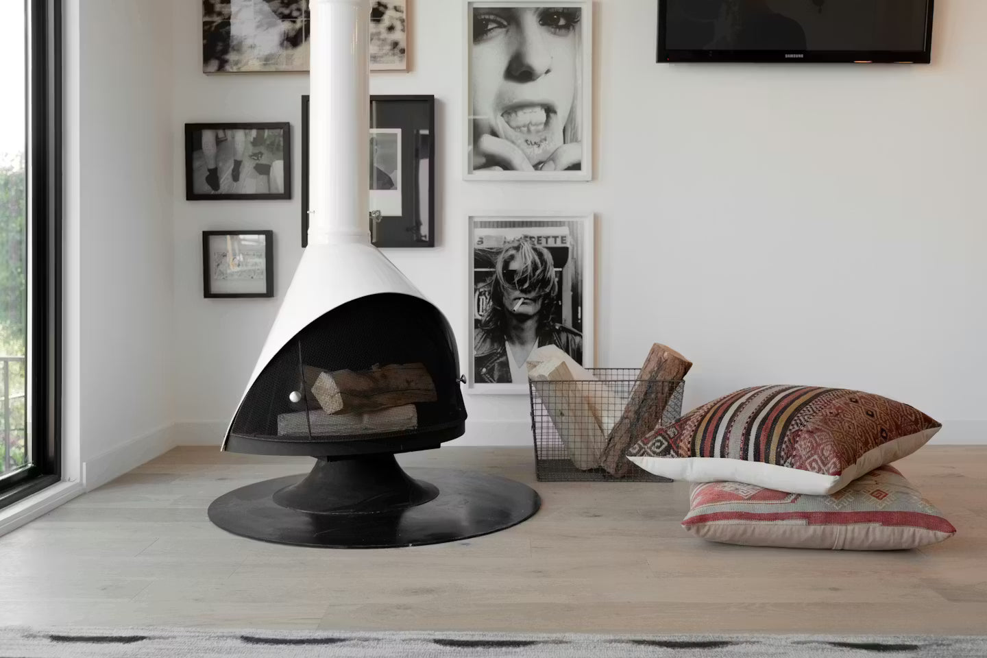 White Coated Top Finish and a Matte Black Base Finish Cone shape Malm 30" zircon wood burning fireplace in a Modern living room with wall art hanging and decorative pillows.
