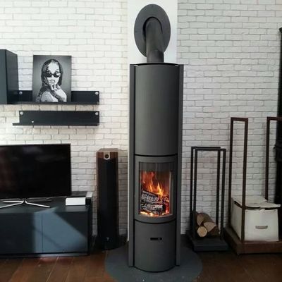 Midcentury Modern MCM black freestanding stove in a living room with white brick walls. wood rack Modern room with large windows, wooden floor, and a freestanding stove. Modern cabin Modern fireplace with a basket of wood on a red and gray wall STUV Modern MCM Fireplace Cylinder fireplace Modern floating fireplace with steel plate for low clearance zero clearance fireplace background Flue Pipe Dura-vent