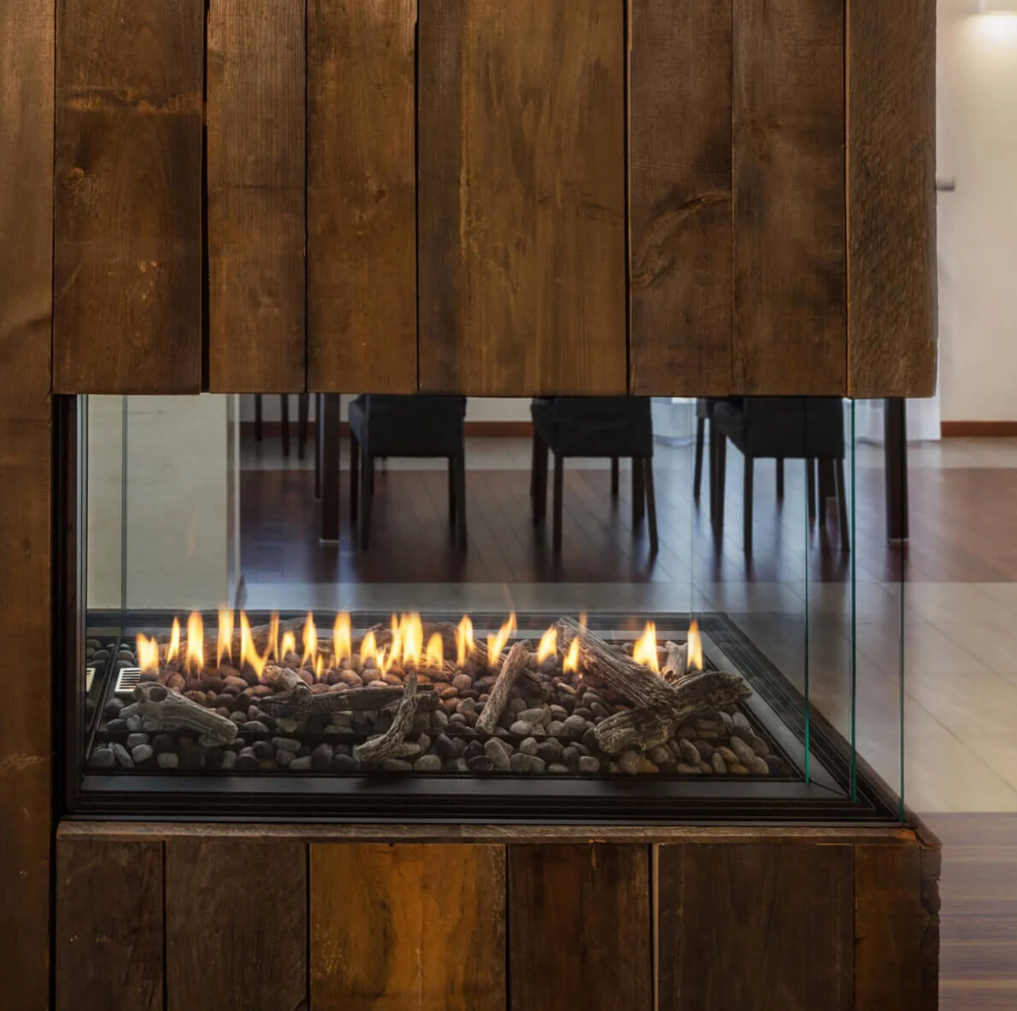 Built-In 3 Sided Montigo Exemplar RP424 See Through Gas Fireplace inserts in a wooden panel with a visible burning media in a modern living room. Direct Vent Indoor Natural gas and propane Fireplace perfect to connect your spaces, room to room or outdoor to indoor. 
High efficient and modern design Linear fireplace.