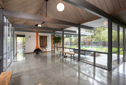 Powder coat top finish and Matte black Base finish malm 30" wood burning fireplace in Modern living room with large glass windows, concrete floor, and outdoor view.