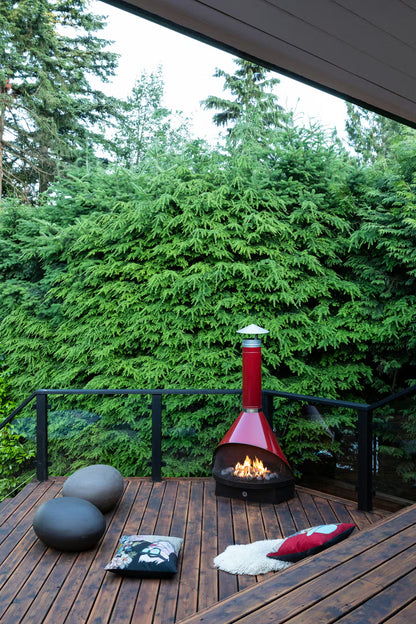 Outdoor View of Red Coated Top Finish and Matte Black Base Finish Cone shape Malm 30" zircon wood burning fireplace  on a wooden deck with green trees in the background.