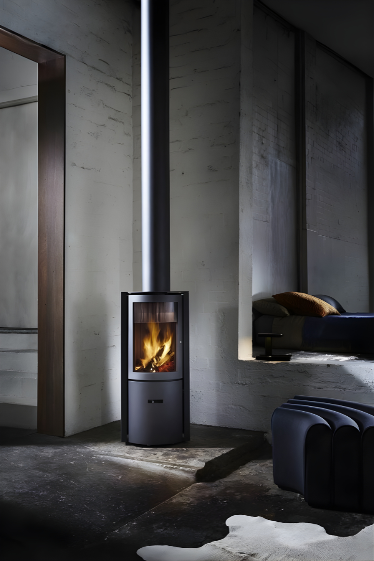 Freestanding Black Stuv 30C wood burning stove in a  dimly lit room with concrete walls and a rug.