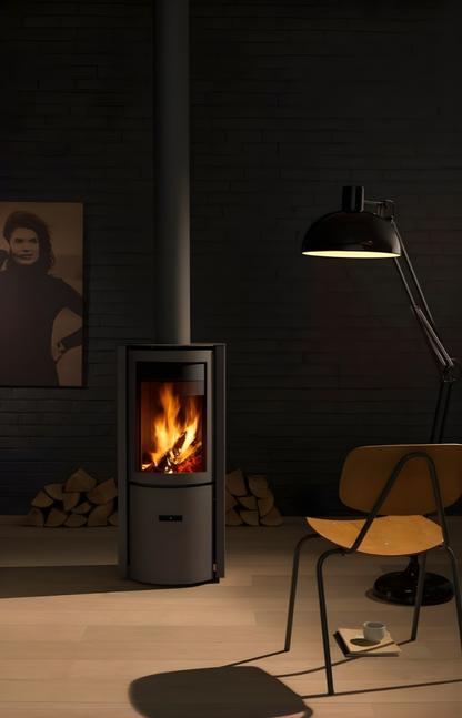 Freestanding Black Stuv 30C wood burning fireplace in dimly lit room with a chair and lamp.