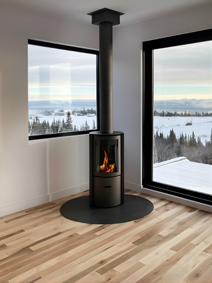 Black Freestanding Stuv 30C in a corner of a room with large windows showing a snowy landscape and a black Chimney connected to the roof.