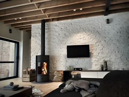 Modern living room with a brick wall, Stuv 30C wood Burning fireplace and a black chimney connected to the roof, and television on the brick wall.