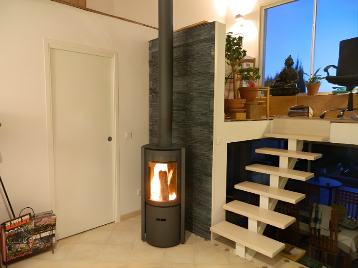 Modern interior with Stuv 30C wood-burning stove and wooden staircase with a glass window showing outdoor nature