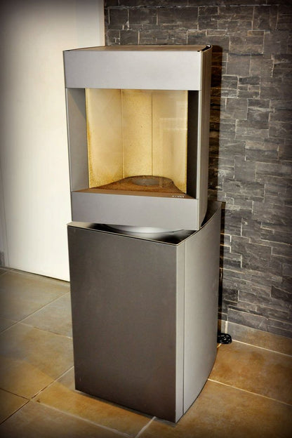 45 degree pivot head of dark oak base free standing Stuv S-P10 pellet stove  in a corner of a modern living room. Modern Indoor remote control and Smart phone control Home heating fireplace. Eco-Friendly, Gentle flame Indoor fireplace. This Fireplace is similar to ComfortBilt Alpine HP40 Pellet Stove, Osburn Volta Pellet Stove, Quadra-Fire Outfitter II Pellet Stove Display Demo,US Stove 1300 Sq ft Wood Pellet Stove, Castle | Serenity Pellet Stove.