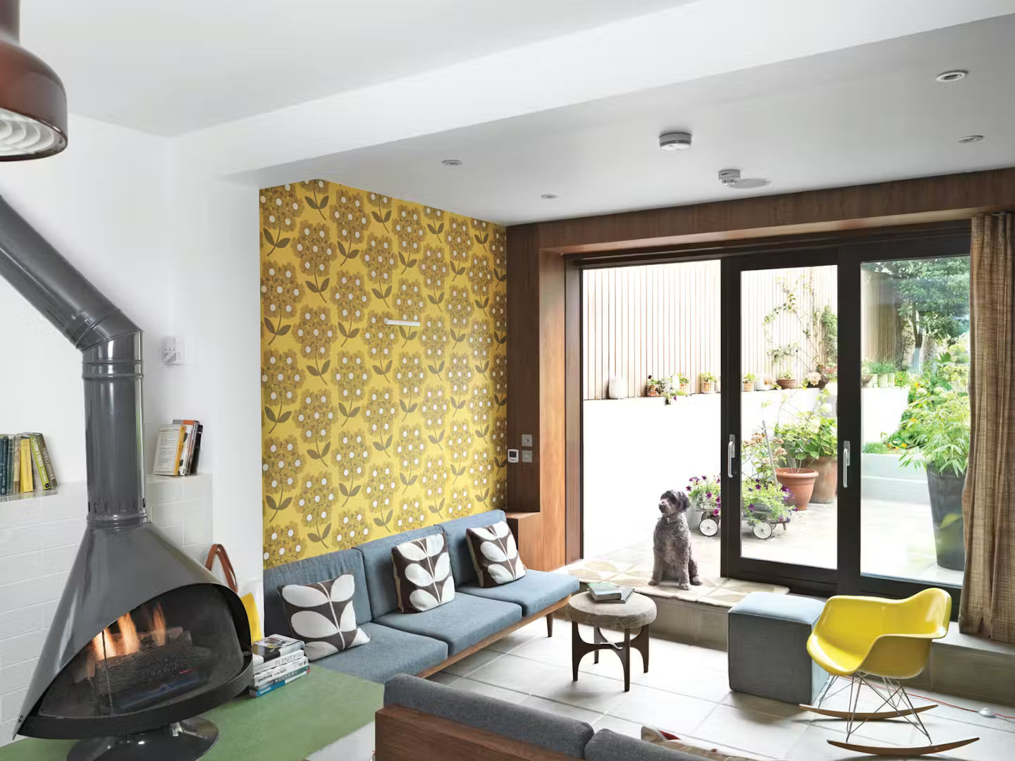 Matte Black Top finish with matching Base finish Malm 30" wood burning fireplace in Modern living room with yellow patterned wallpaper, gray sofa, and yellow chair.