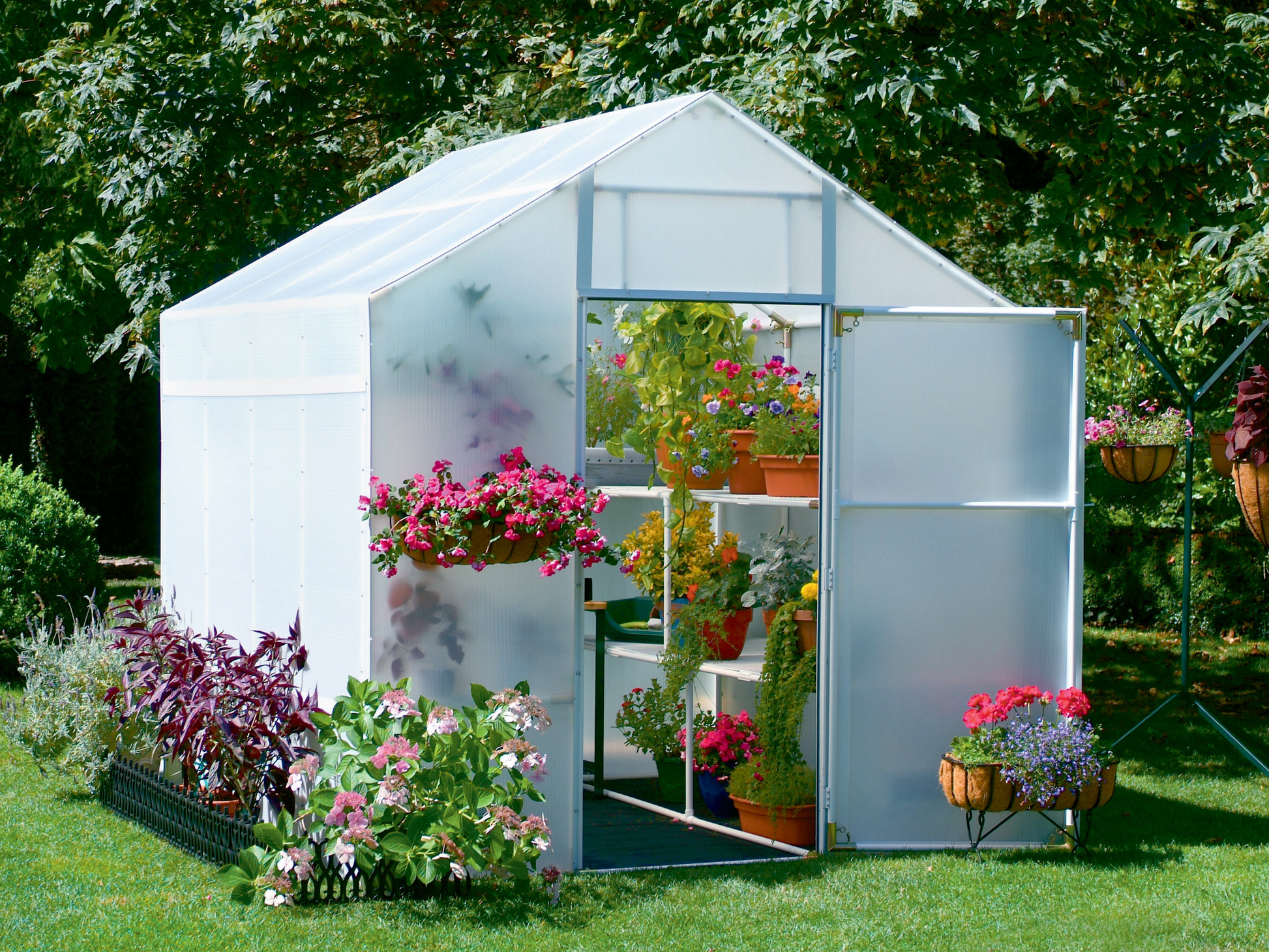 Outside view of 8' x 16' solex garden master with flower flower arranged around the small greenhouse