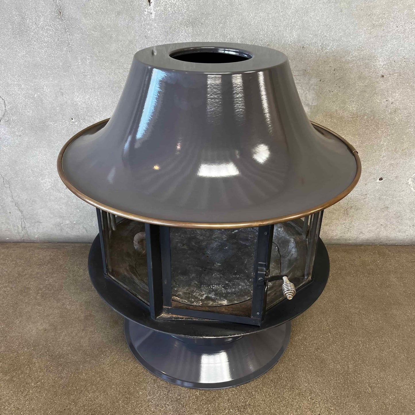 Slate Grey MCM Fireplace Spin a Fire custom color bright colored Carousel zircon, Focus Floating Fireplace hanging fireplace levitating fireplace Metallic outdoor light fixture on a concrete surface with a neutral background