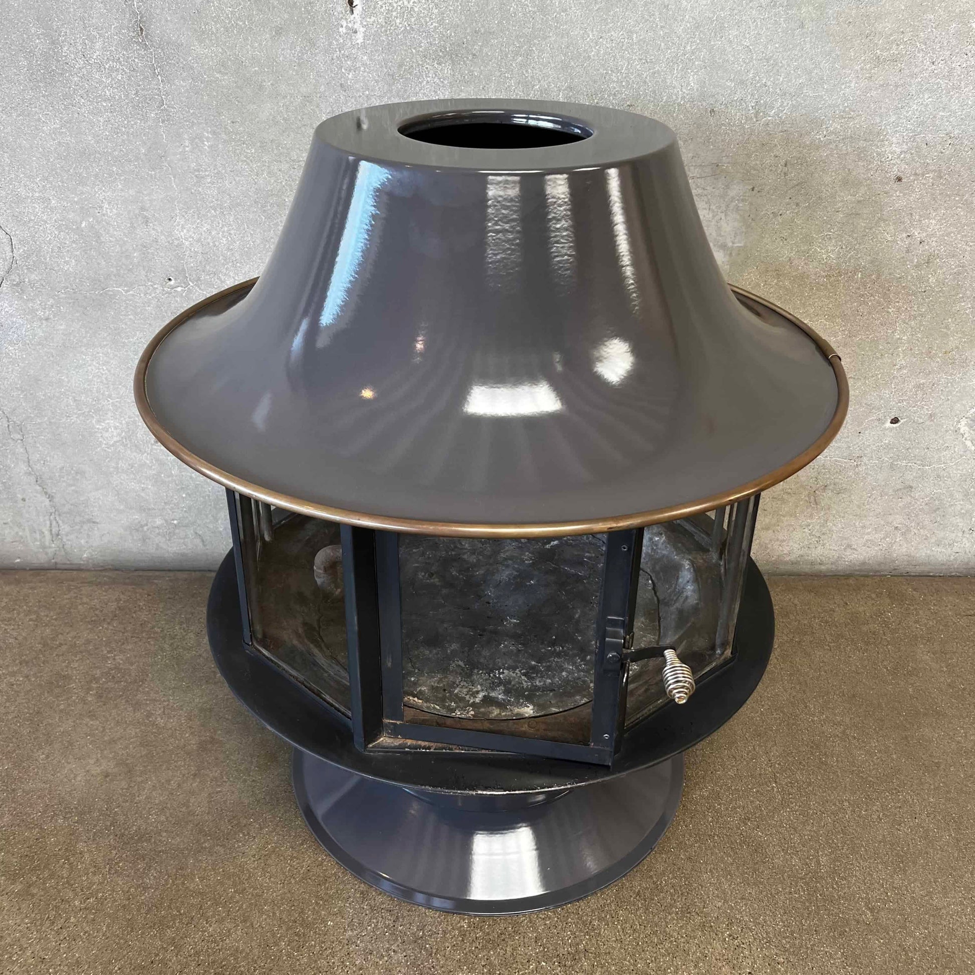Slate Grey MCM Fireplace Spin a Fire custom color bright colored Carousel zircon, Focus Floating Fireplace hanging fireplace levitating fireplace Metallic outdoor light fixture on a concrete surface with a neutral background