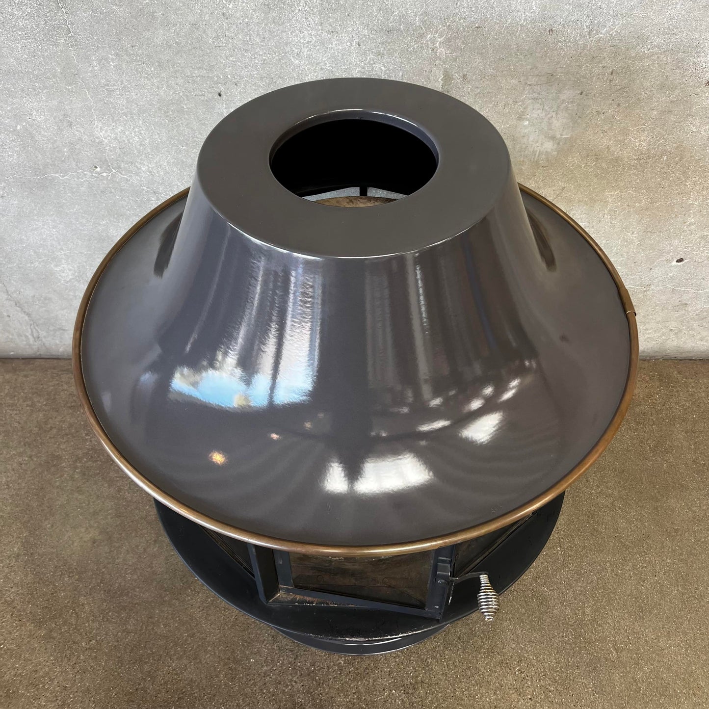 Slate Grey MCM Fireplace Spin a Fire custom color bright colored Carousel zircon, Focus Floating Fireplace hanging fireplace levitating fireplace Metallic outdoor light fixture on a concrete surface with a neutral background 