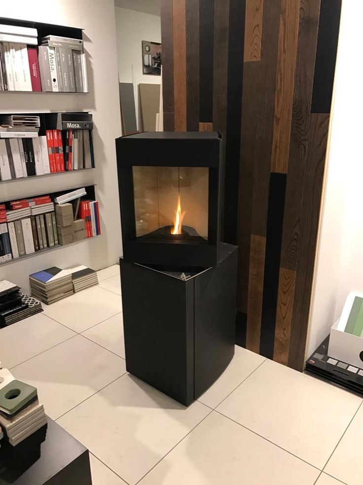 Pivot head dark oak base free standing Stuv S-P10 pellet stove with visible burning flame in a corner of a modern living room. Modern Indoor remote control and Smart phone control Home heating fireplace. Eco-Friendly, Gentle flame Indoor fireplace. This Fireplace is similar to ComfortBilt Alpine HP40 Pellet Stove, Osburn Volta Pellet Stove, Quadra-Fire Outfitter II Pellet Stove Display Demo,US Stove 1300 Sq ft Wood Pellet Stove, Castle | Serenity Pellet Stove.