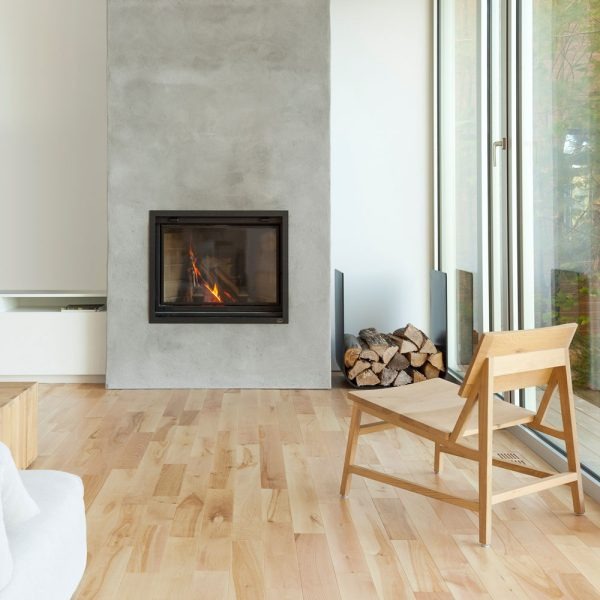 Valcourt Antoinette Black Built-in indoor wood burning fireplace with mansory trim, guillotine-style door and  visible wood burning flame in a modern living room with large window. Heating area up to 1,000 sq. ft, EPA qualified. Antoinette Modern hearth fireplace is similar to Majestic Biltmore Wood Burning Fireplace - 50", Supreme Astra Single-Sided Wood Burning Fireplace, Empire Aspen Traditional Wood Burning Fireplace, Montigo Divine Bay H38DFPRC Direct Vent Gas Fireplace, Modern Flames Orion.