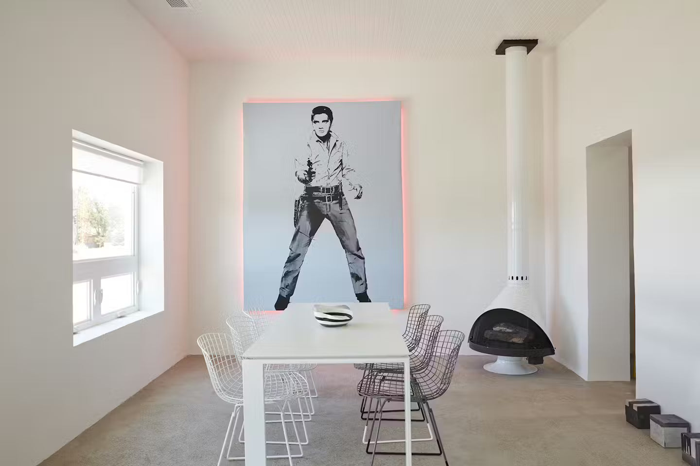 White Powder coat Top finish and matching base malm 30" zircon wood burning fireplace in a corner of Modern dining room with a large framed picture of a man on the wall.