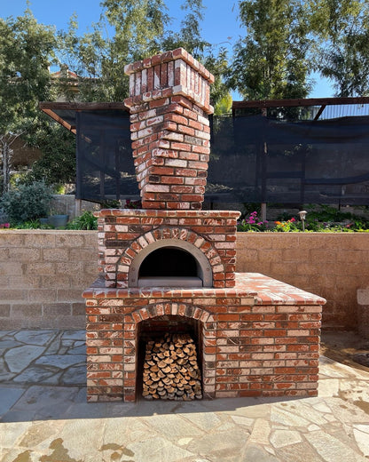 Brick outdoor Wood Gas Hybrid pizza oven with wood storage on a patio outdoor kitchen setup ready to make your perfect outdoor kitchen. CBO 750 Hybrid Pizza Oven, dual fuel pizza oven, outdoor wood fired pizza oven, natural gas pizza oven, DIY pizza oven kit, residential countertop pizza oven, Chicago Brick Oven, backyard pizza oven, outdoor kitchen pizza oven, hybrid pizza oven for home. Alfa Pizza Oven 3 pizze but better made in America 