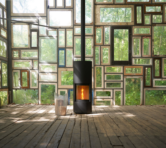 Matte Black Stûv P-20S Freestanding Modern Indoor pellet burning stove in large close spade with visible burning flame and pellet twin set container beside the fireplace. Elegance, silence, performance, ease of use and maintenance Fireplace. This pellet stove is similar to Stûv 30 Wood Stove | Compact Glass Fire Screen Stove | 360° Adjustable Rotating Wood Burning Stove With Double Walls, Osburn Aduro H1 Pellet/Wood Combo Hybrid Free Standing Stove SF00401, Comfortbilt Pellet Stoves HP50 Brown Modern Design