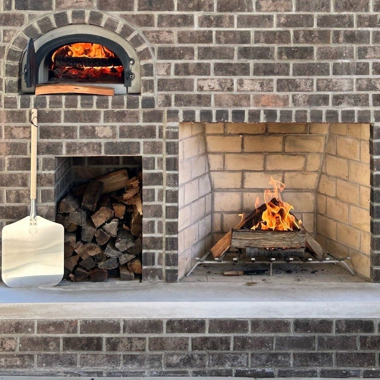 Brick outdoor Wood fired pizza oven with wood storage on a patio outdoor kitchen setup ready to make your perfect outdoor kitchen. CBO 750 Hybrid Pizza Oven, dual fuel pizza oven, outdoor wood fired pizza oven, natural gas pizza oven, DIY pizza oven kit, residential countertop pizza oven, Chicago Brick Oven, backyard pizza oven, outdoor kitchen pizza oven, hybrid pizza oven for home. Alfa Pizza Oven 3 pizze but better made in America  with built in Gas BBQ LPG NG Pizza Oven Wood Burning Ooni Gozney