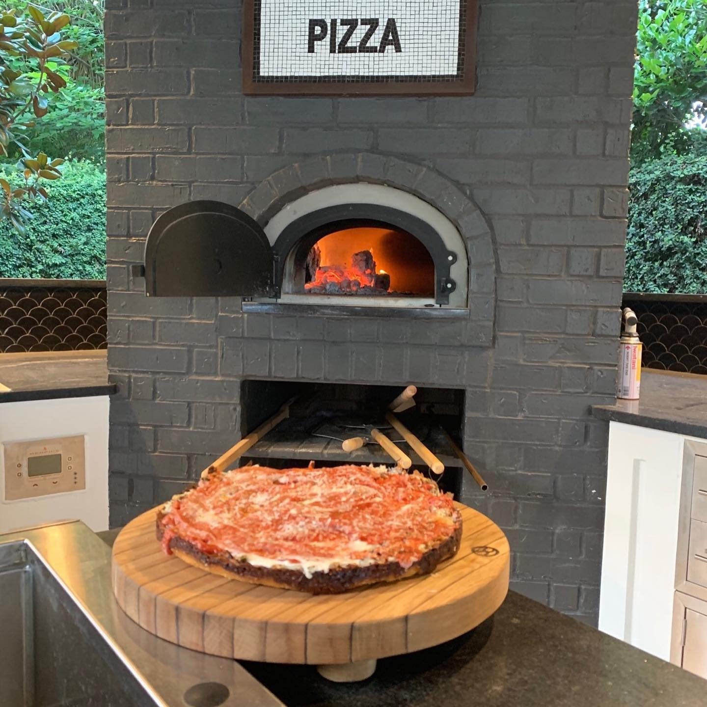 Brick outdoor Wood Wood fired pizza oven with wood storage on a patio outdoor kitchen setup ready to make your perfect outdoor kitchen. CBO 750 Hybrid Pizza Oven, dual fuel pizza oven, outdoor wood fired pizza oven, natural gas pizza oven, DIY pizza oven kit, residential countertop pizza oven, Chicago Brick Oven, backyard pizza oven, outdoor kitchen pizza oven, hybrid pizza oven for home. Alfa Pizza Oven 3 pizze but better made in America  with built in Gas BBQ LPG NG Pizza Oven Wood Burning Ooni Gozney