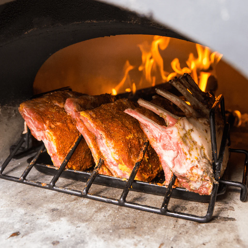 Brick outdoor Wood fired pizza oven with rib being cooked inside the oven. CBO 750 Hybrid Pizza Oven, dual fuel pizza oven, outdoor wood fired pizza oven, natural gas pizza oven, DIY pizza oven kit, residential countertop pizza oven, Chicago Brick Oven, backyard pizza oven, outdoor kitchen pizza oven, hybrid pizza oven for home. Alfa Pizza Oven 3 pizze but better made in America  with built in Gas BBQ LPG NG Pizza Oven Wood Burning Ooni Gozney
