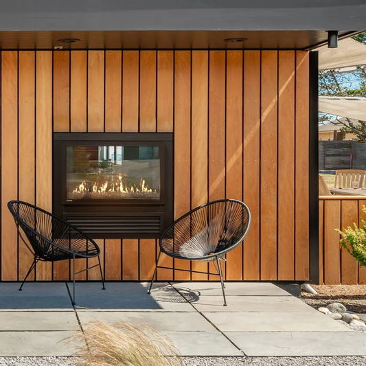 Outdoor setting with Montigo Exemplar Indoor/Outdoor Built-In Direct Vent Gas Fireplace Inserts into a wooden wall Panel. See Through Modern Fireplace with visible flame and black surrounds suitable for Home and commercials.