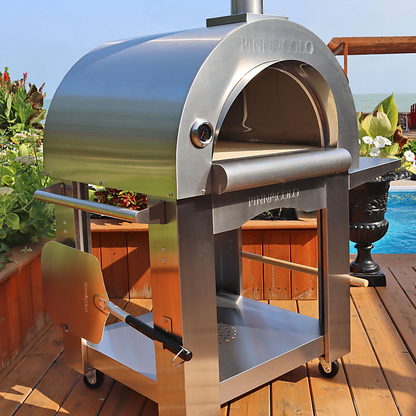 Outdoor view of pinnacolo wood-fired stainless steel  pizza oven on a wooden deck with a pool in the background