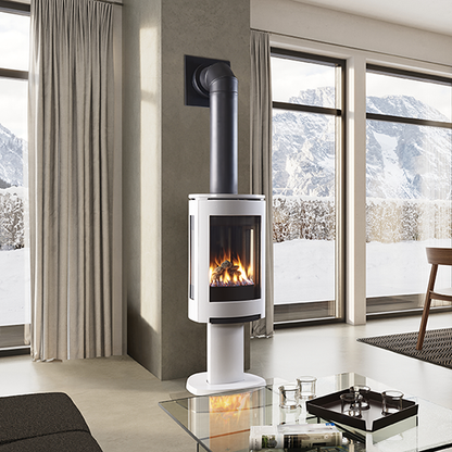 Modern Linen Color freestanding three sided GF Jotul 370 DV Gas stove in a living room with a Elbow Flue Pipe Direct Vent to the wall with  large windows showing a snowy landscape.