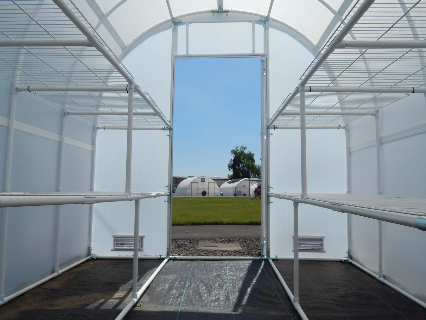 Interior view of 8' X 8' solexx gardeners Oasis Outdoor greenhouse with Open Closeable door and two base vents 