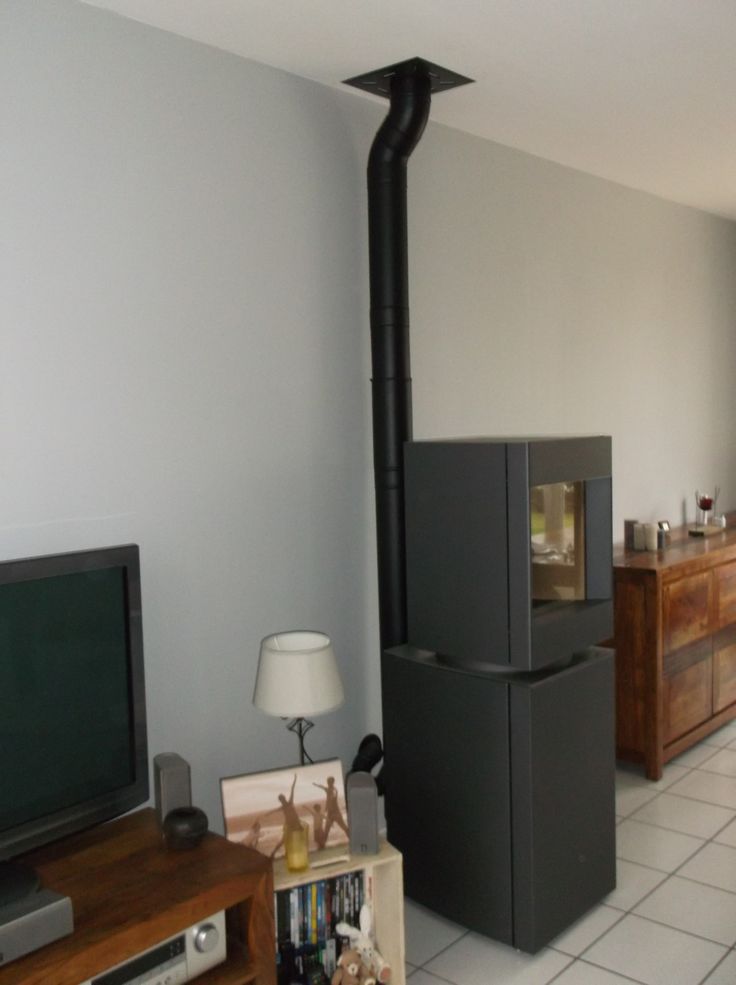 Dark oak base free standing Stuv S-P10 pellet stove with visible burning flame in a corner of a modern living room. Modern Indoor remote control and Smart phone control Home heating fireplace. Eco-Friendly, Gentle flame Indoor fireplace. This Fireplace is similar to ComfortBilt Alpine HP40 Pellet Stove, Osburn Volta Pellet Stove, Quadra-Fire Outfitter II Pellet Stove Display Demo,US Stove 1300 Sq ft Wood Pellet Stove, Castle | Serenity Pellet Stove.