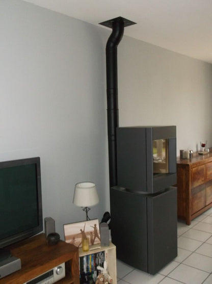 Dark oak base free standing Stuv S-P10 pellet stove with visible burning flame in a corner of a modern living room. Modern Indoor remote control and Smart phone control Home heating fireplace. Eco-Friendly, Gentle flame Indoor fireplace. This Fireplace is similar to ComfortBilt Alpine HP40 Pellet Stove, Osburn Volta Pellet Stove, Quadra-Fire Outfitter II Pellet Stove Display Demo,US Stove 1300 Sq ft Wood Pellet Stove, Castle | Serenity Pellet Stove.