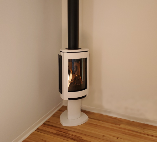 Linen Jotul GF 370 DV Freestanding Gas Stove with a vent to the roof in a corner of white painted room and wooden floor