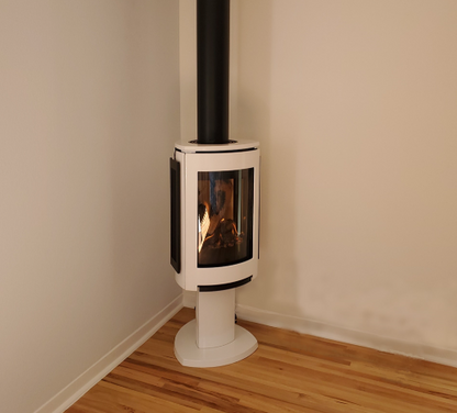 Linen Jotul GF 370 DV Freestanding Gas Stove with a vent to the roof in a corner of white painted room and wooden floor